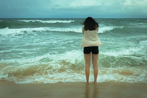 Sad depressed lonely woman standing in ocean crying